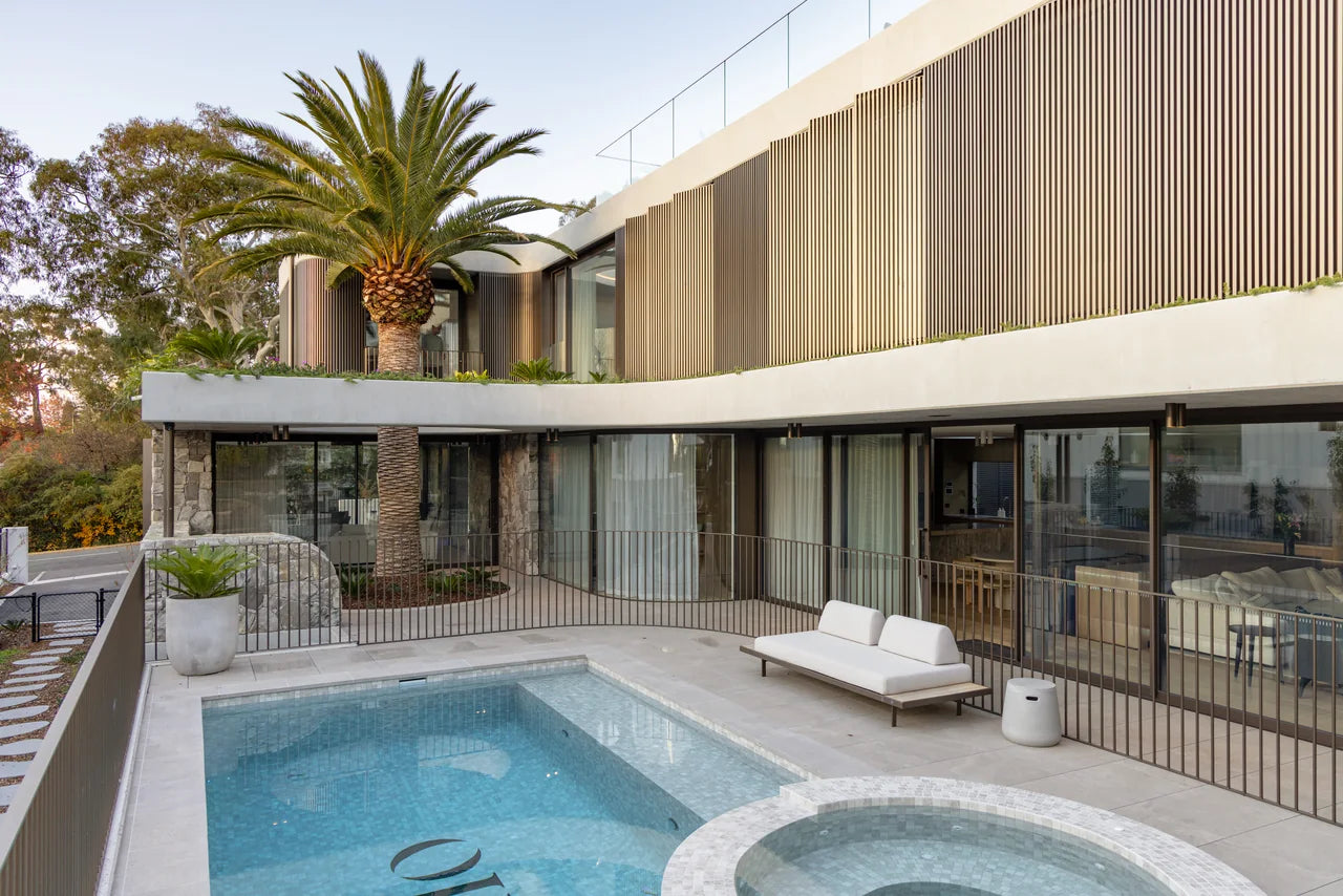 Outdoor pool and tiled terrace beside a curved timber facade